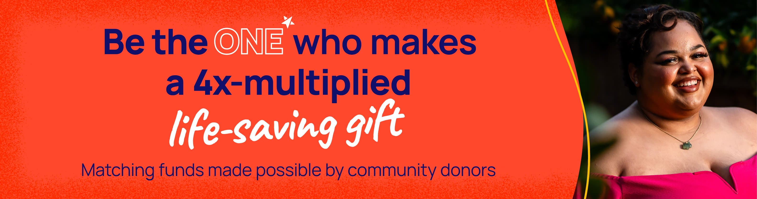 A young person standing in front of greenery wearing an off-the-shoulder shirt, smiling at the camera. Be the one who makes a 4x-multiplied life-saving gift.